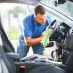 A man scrubbing his steering wheel with a microfiber cloth