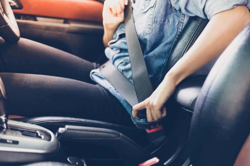 Woman fastening seat belt in the car.