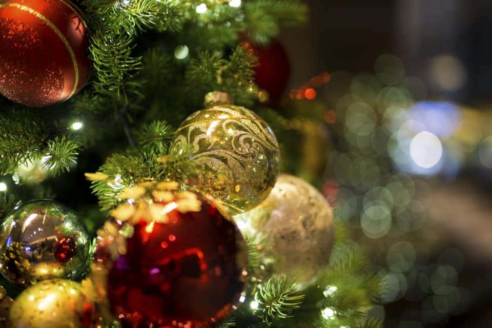 A close up of red and gold christmas ornaments and christmas lights on a christmas tree.