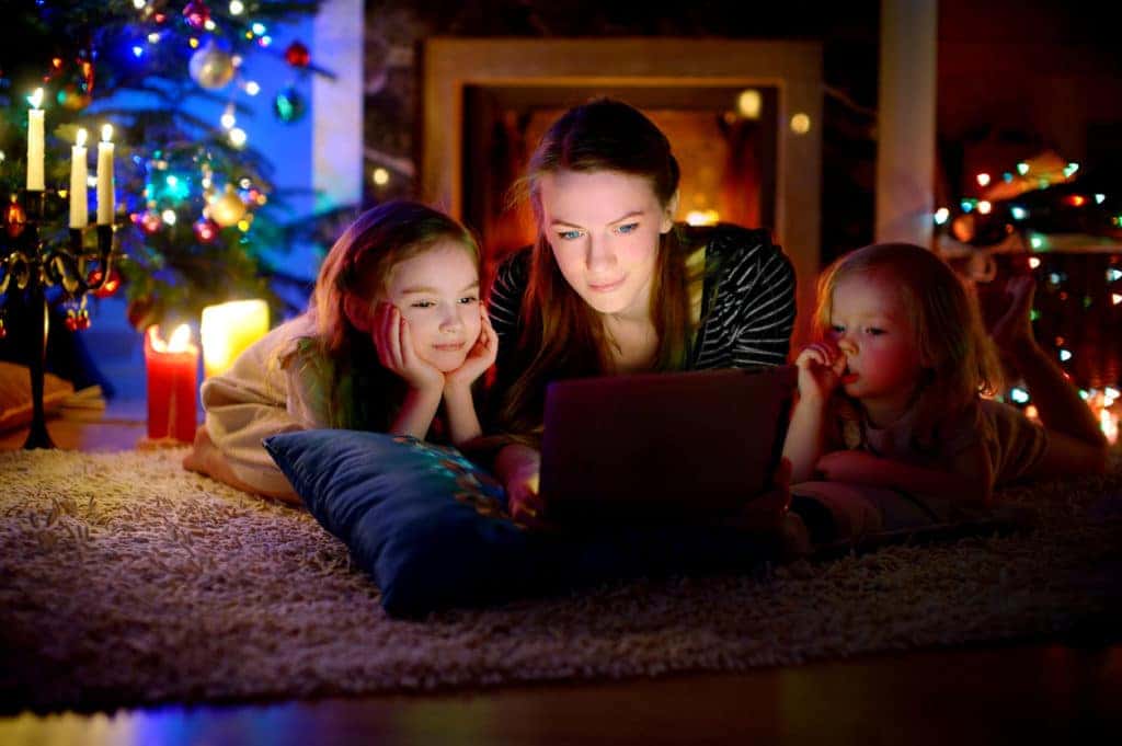 Mother and daughters using laptop with Christmas tree in background