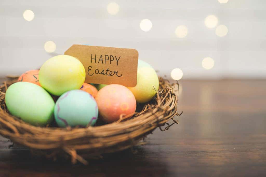 Woven stick basket of colored eggs with handmade Happy Easter sign.