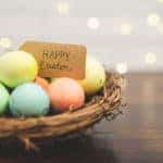 Woven stick basket of colored eggs with handmade Happy Easter sign.
