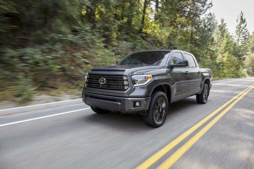 Grey Tundra truck on the road through a wooded area