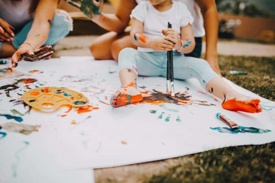 Family painting a white sheet in the yard