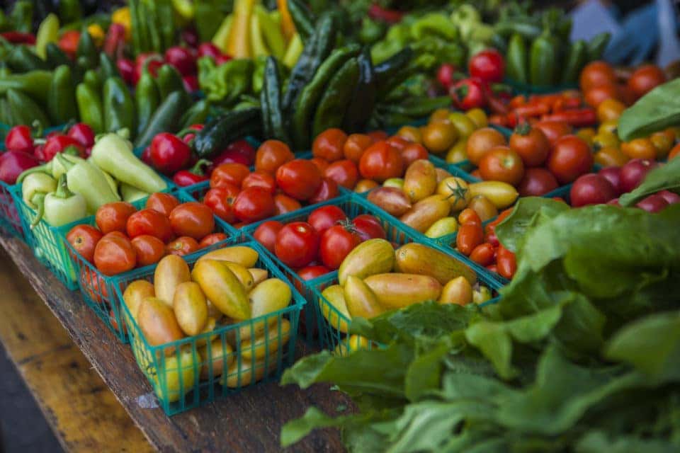 Vegetables with various tomatoes, pimentos and lettuce on market stall.