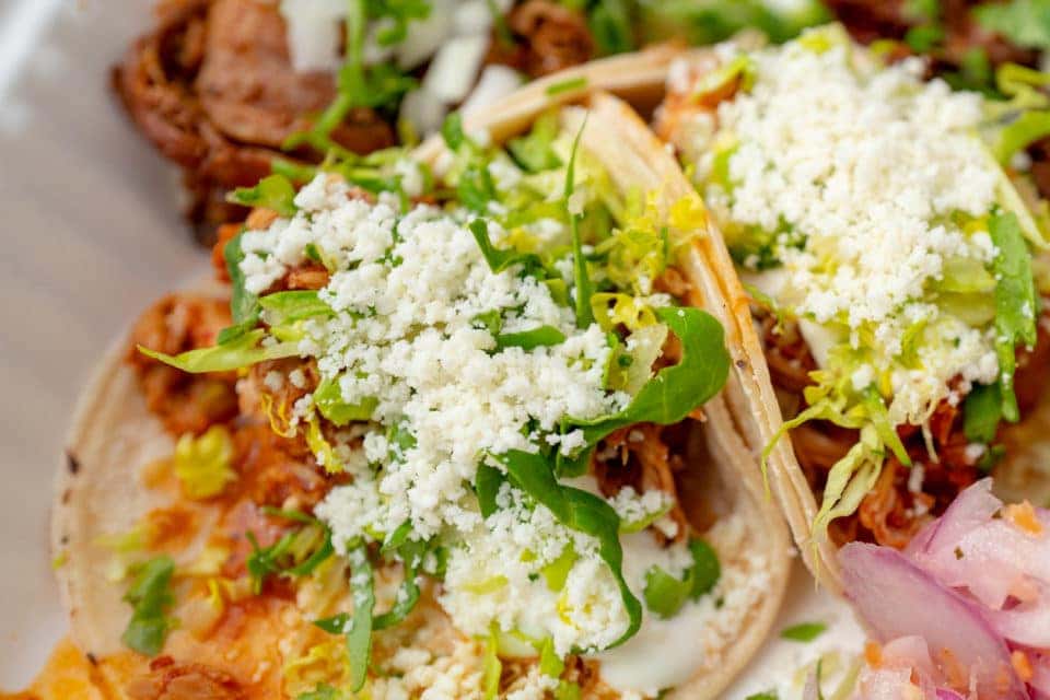 Close-up of tacos with chicken, cheese, with pickled onions and lime wedges