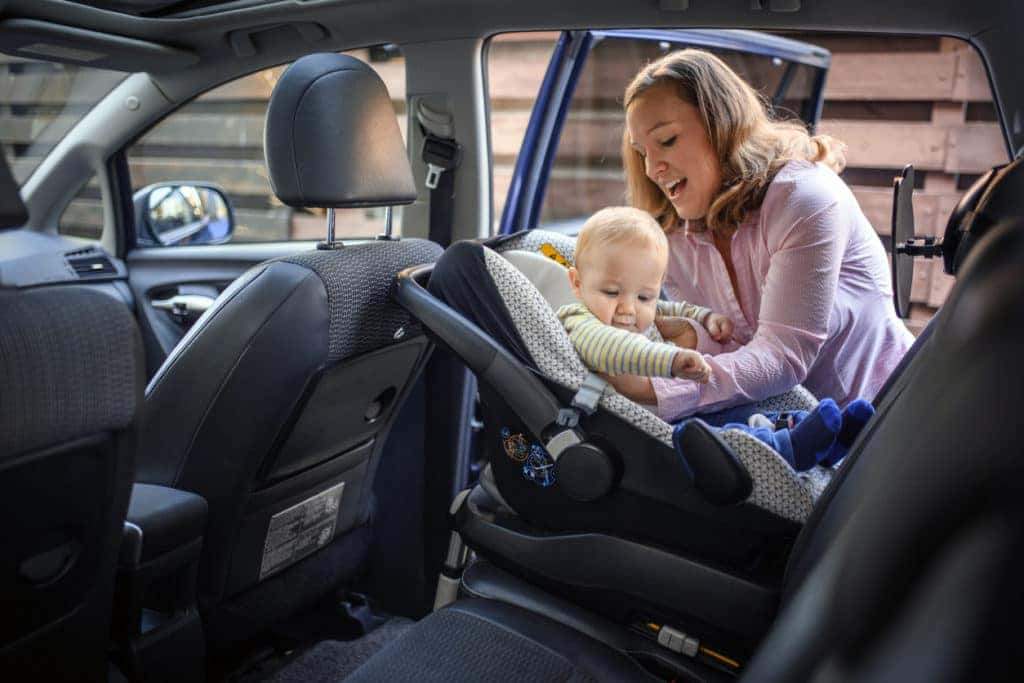 Mother putting her child in a car safety seat