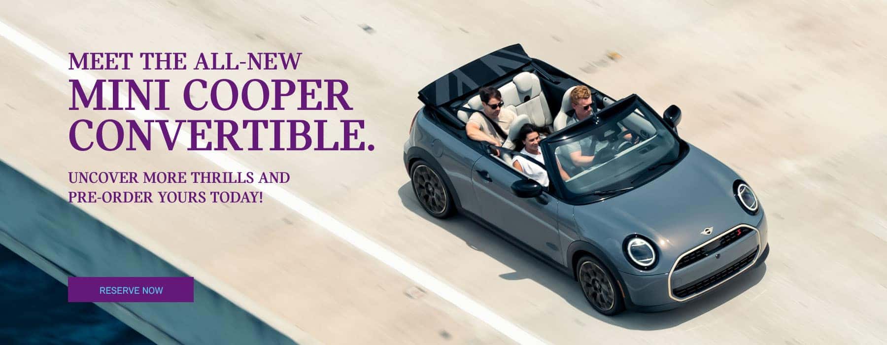 Ariel right view of a grey MINI convertible driving down a highway.