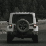 Jeep driving on a winding mountain road in the Pacific Northwest with brake lights on.