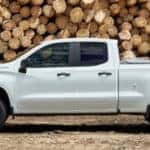 2019 Chevrolet Silverado 1500 in white parked in front of a large wood pile