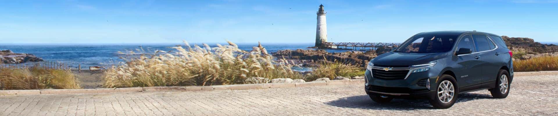 Blue 2024 Chevy Equinox parked near a lighthouse and beach