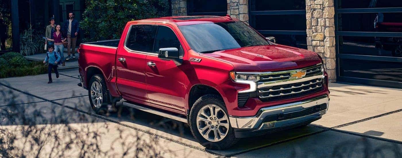 A red 2024 Chevy Silverado 1500 Z71 parked outside a family home.