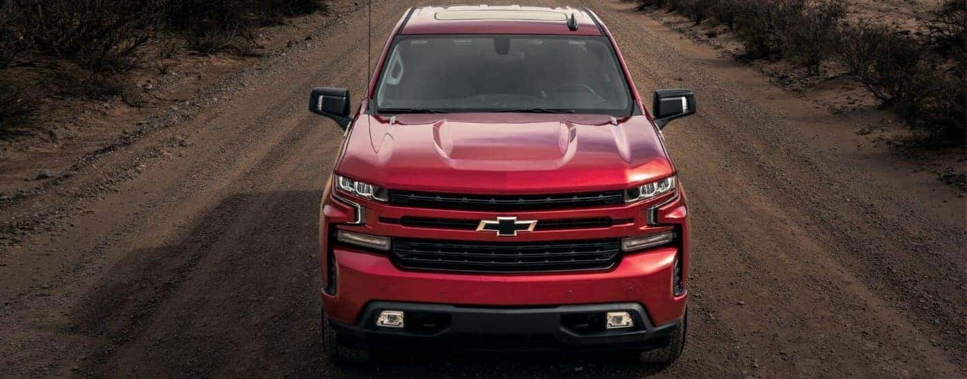 A red 2023 Chevy Silverado 1500 RST driving down a dirt road.