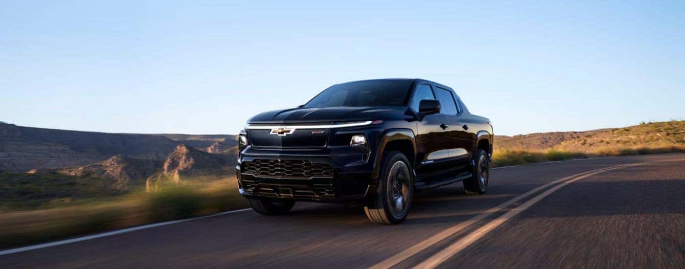 A black 2025 Chevy Silverado EV RST driving on an open road.
