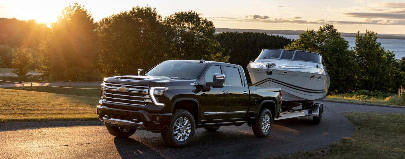 A black 2025 Chevy Silverado 2500 for sale is shown towing a boat.