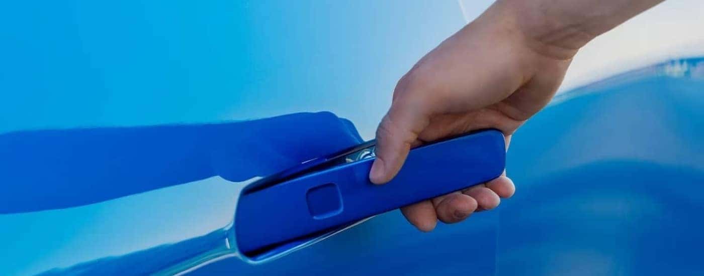 A person is shown opening the door of a blue 2024 Chevy Equinox EV for sale near Fredericksburg.