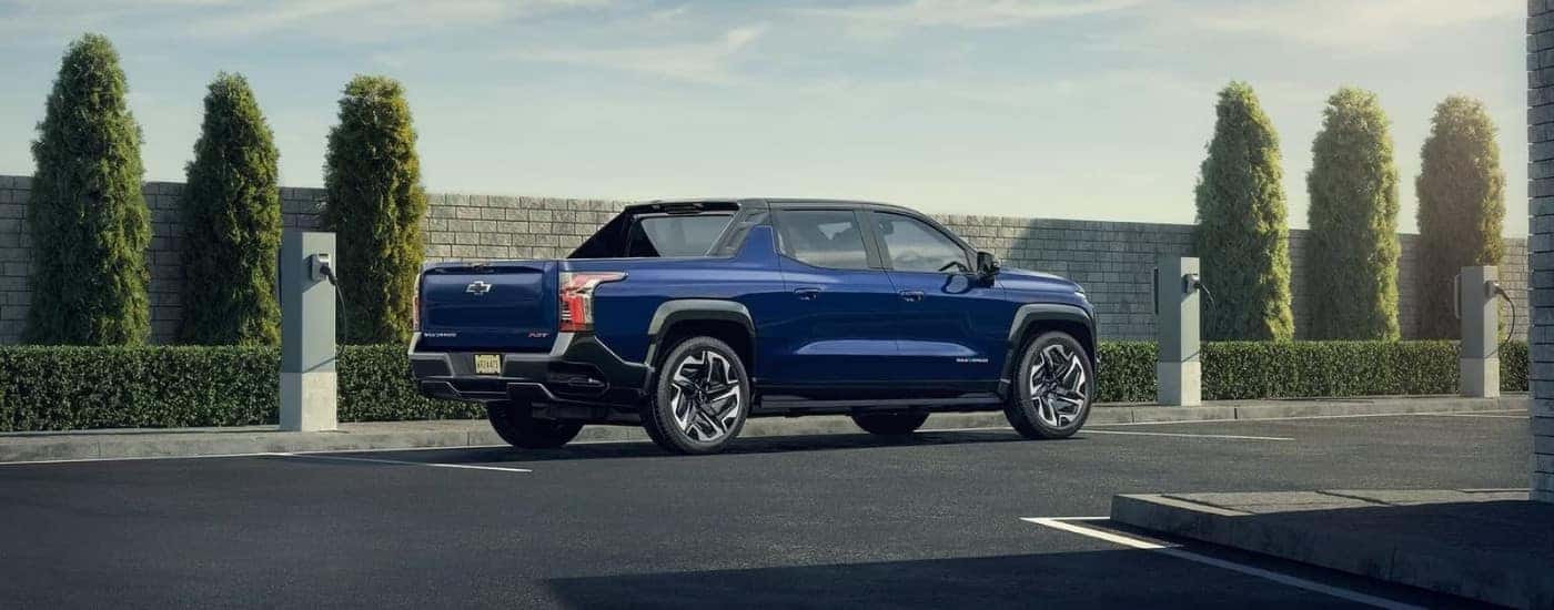A blue 2024 Chevy Silverado EV for sale near Fredericksburg parked near charging stations.