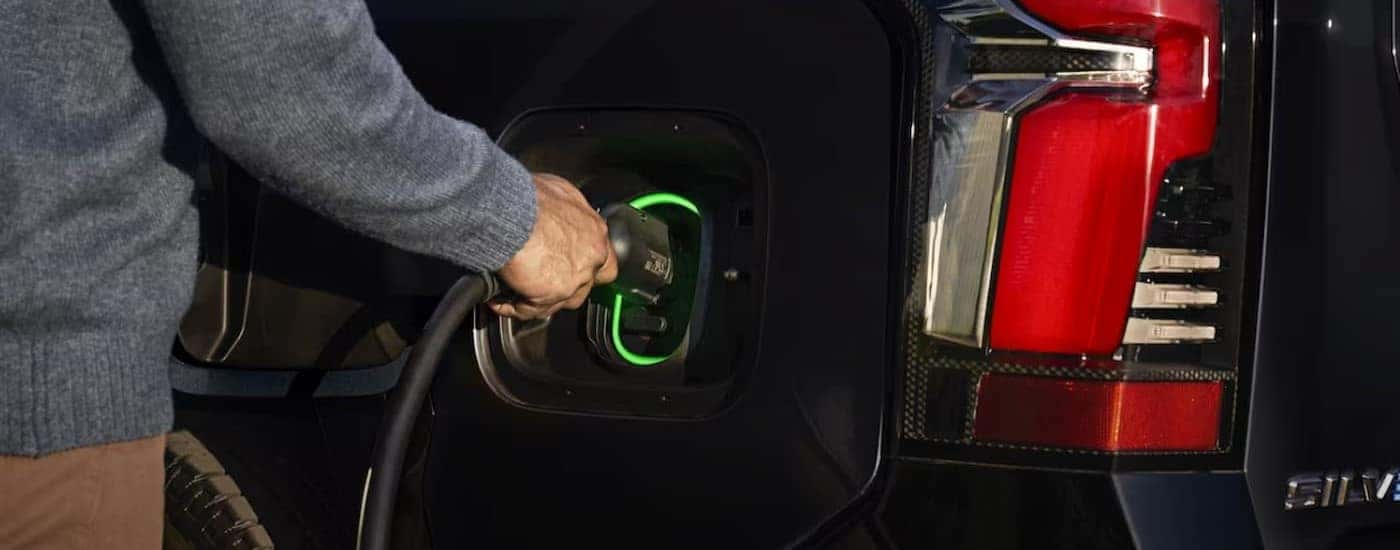A person charging a 2024 Chevy Silverado EV.
