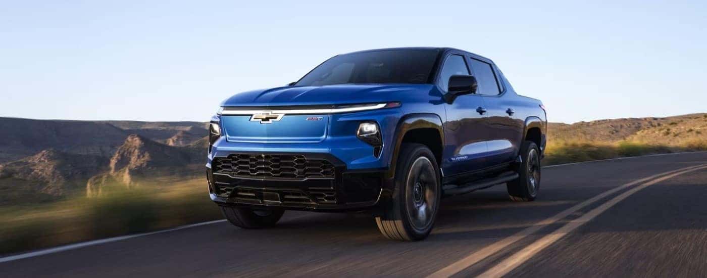 A blue 2024 Chevy Silverado EV RST driving down an open road.