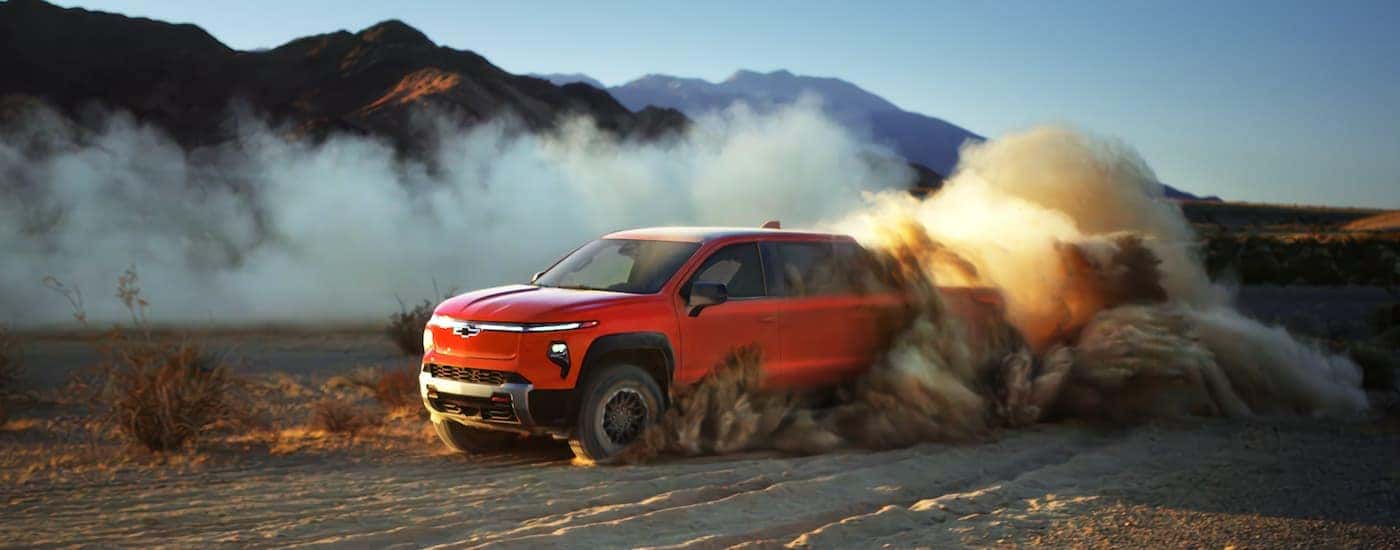 A red 2025 Chevy Silverado EV for sale near Mechanicsville driving off-road in a desert.