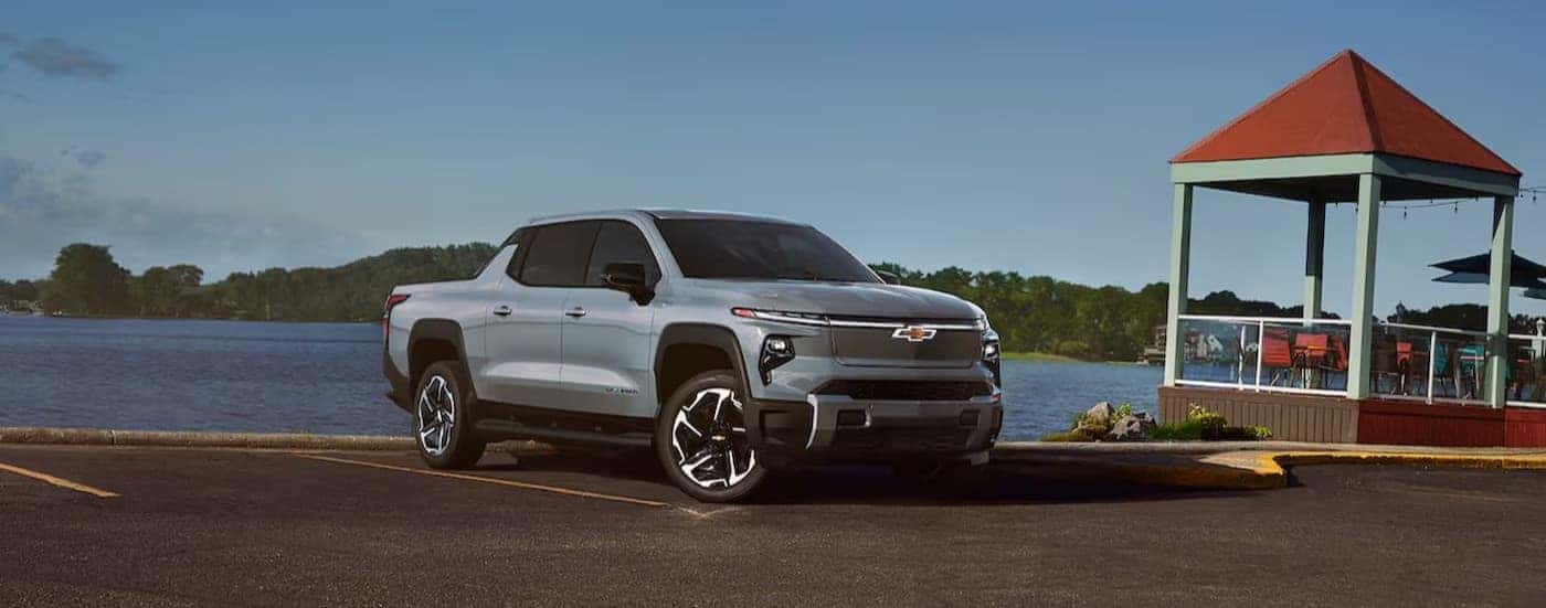 A silver 2024 Chevy Silverado EV for sale near Midlothian parked near a lake.