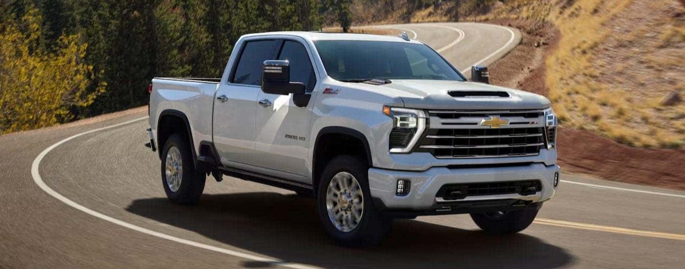 A white 2025 Chevy Silverado 2500 for sale near Fredericksburg driving on a highway.