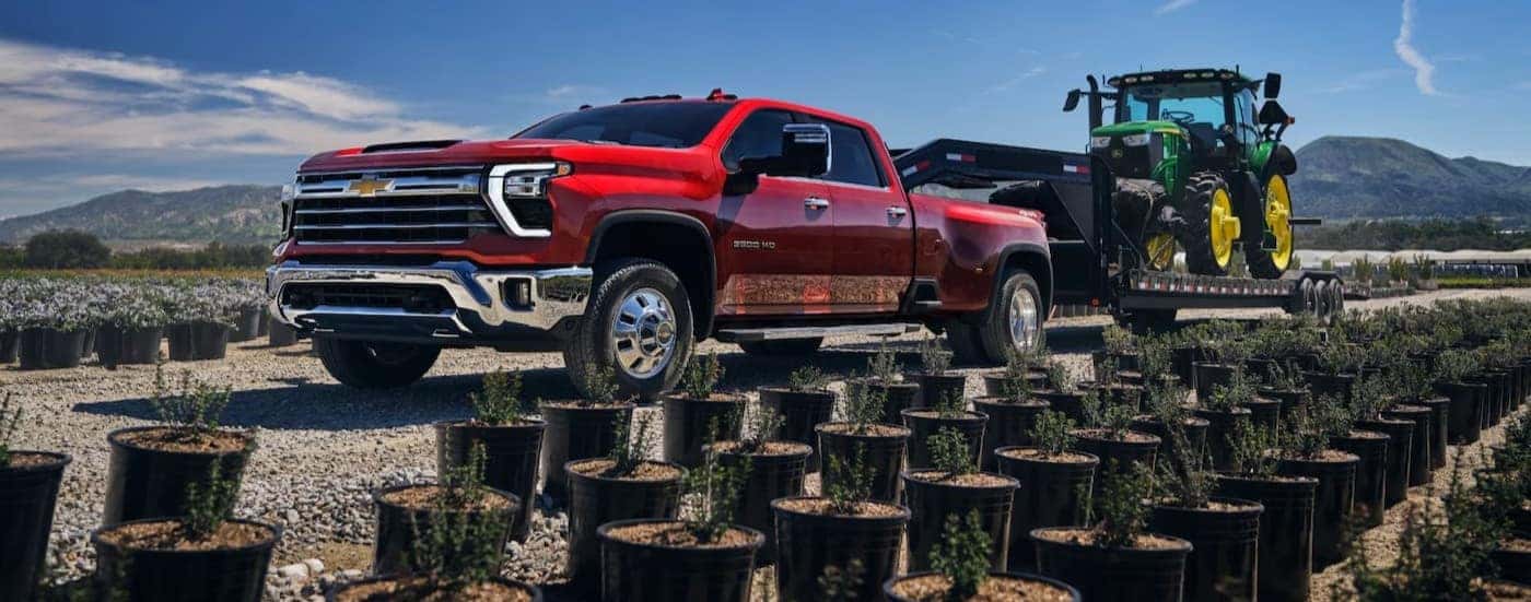 A red 2025 Chevy Silverado 3500 towing a trailer.