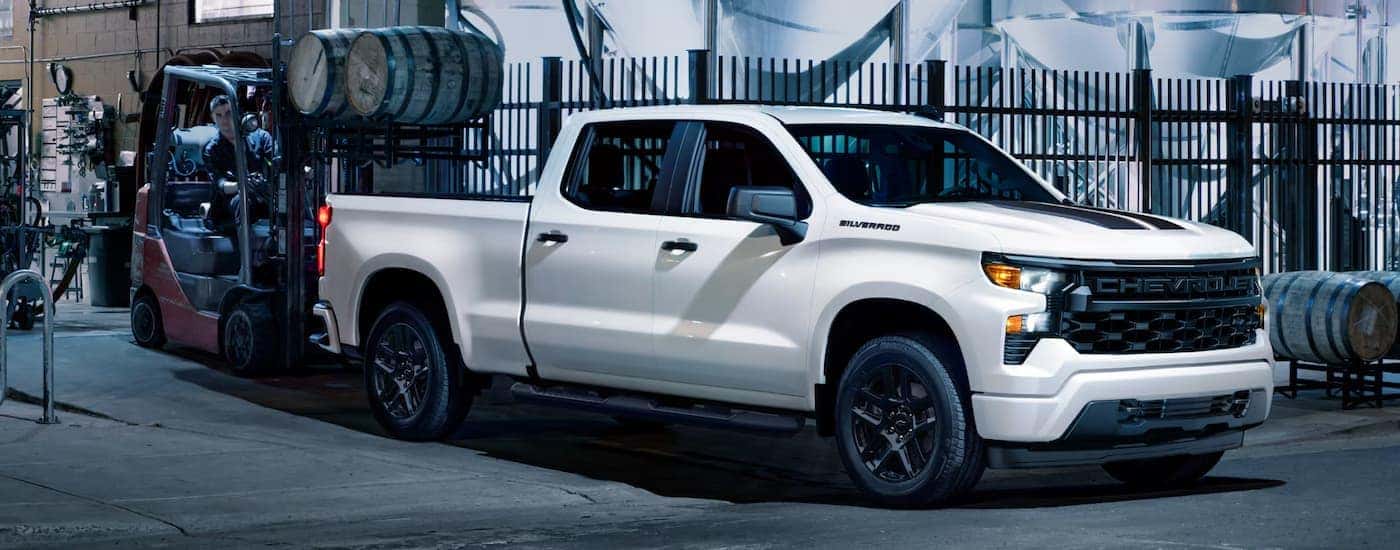 White 2025 Chevy Silverado 1500 Custom parked near a forklift