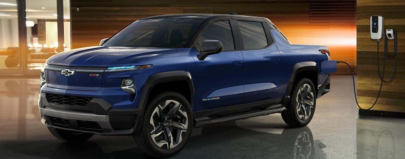 Blue 2024 Chevy Silverado 1500 EV charging in a garage