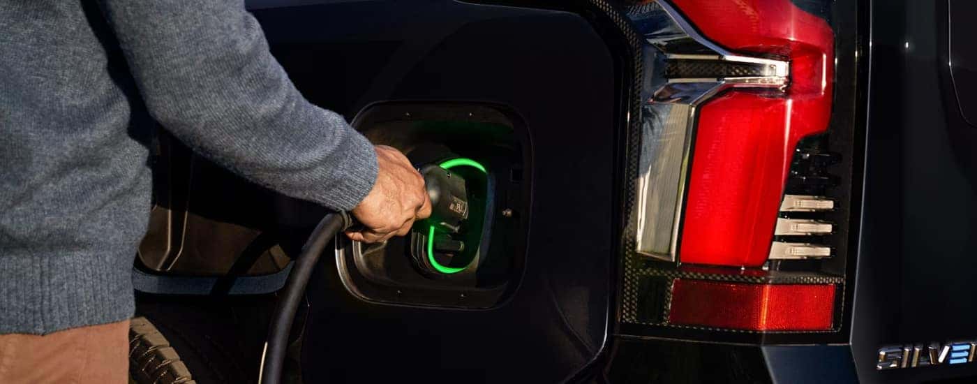 Person charging a black 2025 Chevy Silverado EV
