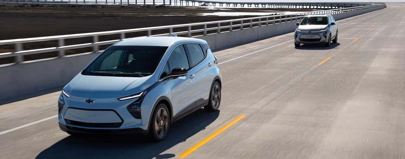 Blue 2022 Chevy Bolt EV and tan Bolt EUV driving to look at EVs for sale near Montrose.