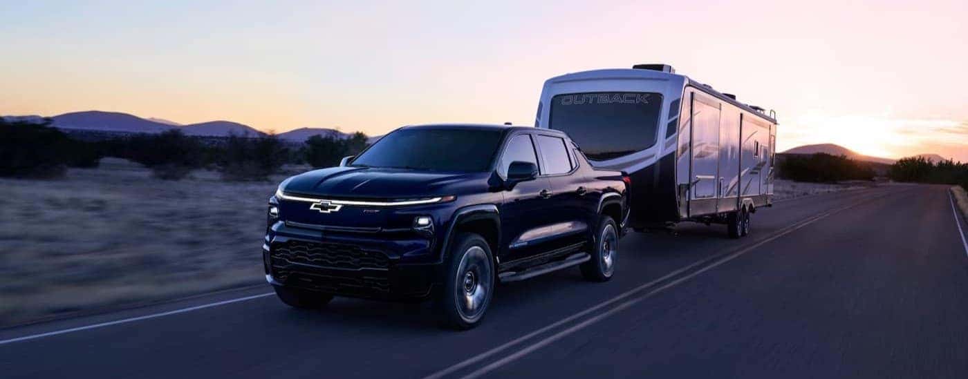 A black 2025 Chevy Silverado EV RST towing a trailer.