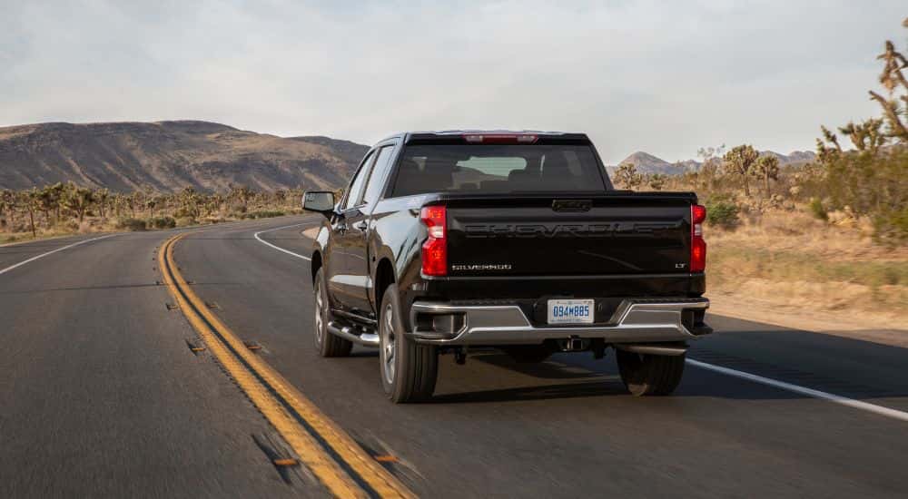 Black 2022 Chevy Silverado 1500 LT from the rear driving to see a used chevy for sale.