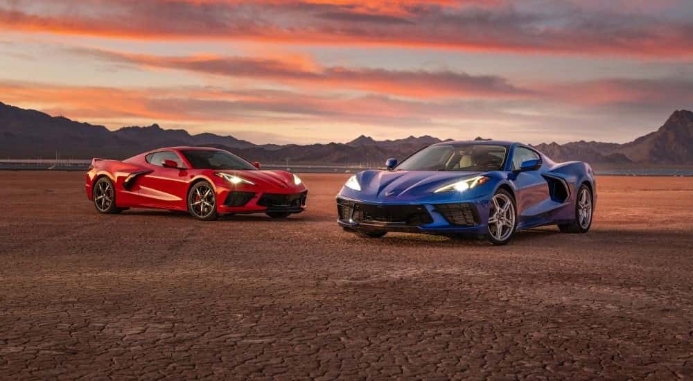Two 2020 Chevy Corvette C8 parked side by side in front of a sunset.