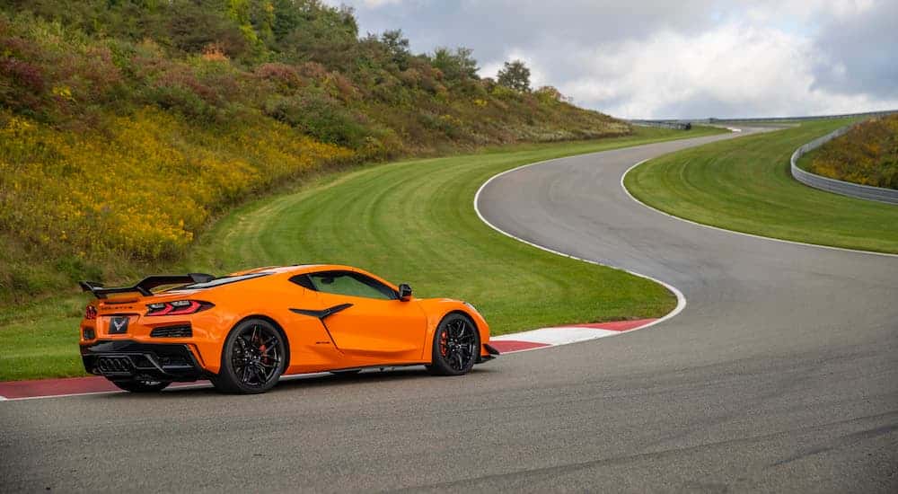 Orange 2023 Chevy Corvette C8 making a turn around a race track.