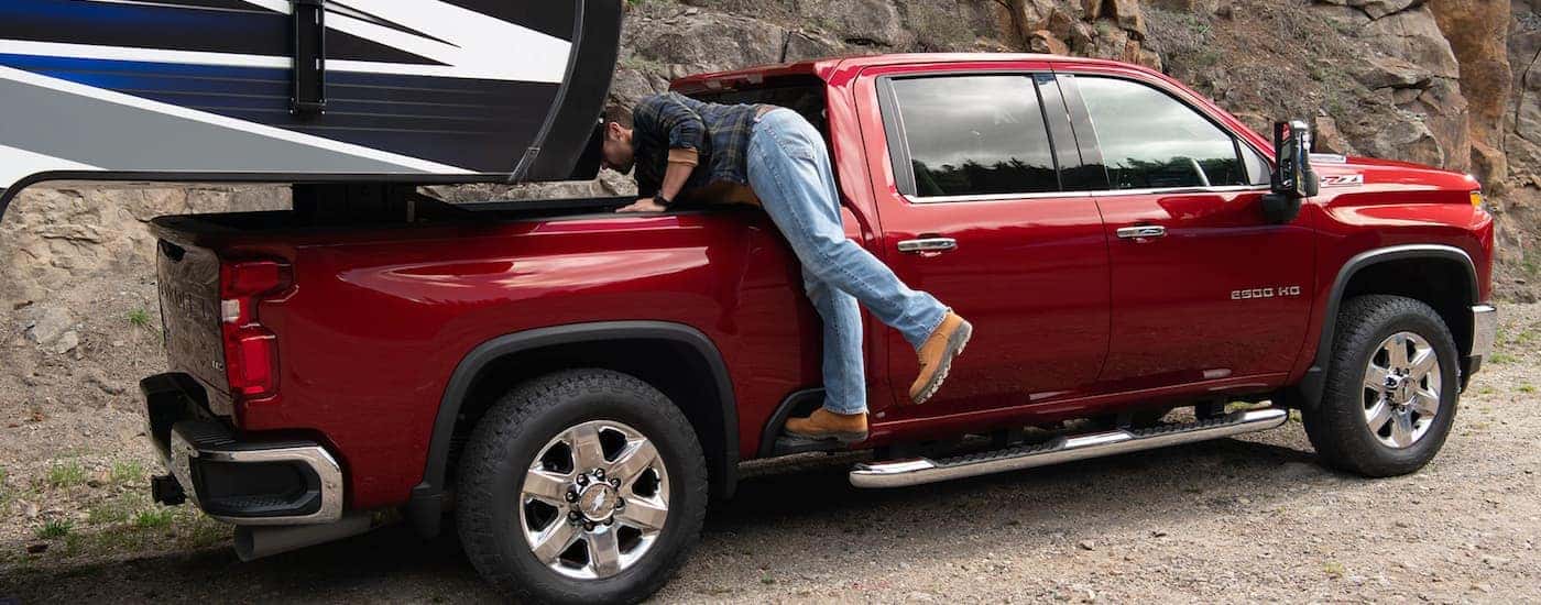 A person reaches into the bed of their red 2020 Chey Silverado 2500