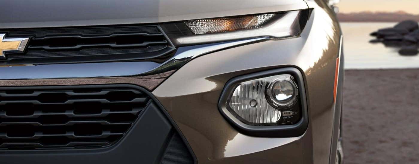 Headlight of a brown 2021 Chevy Trailblazer parked outside a car dealership