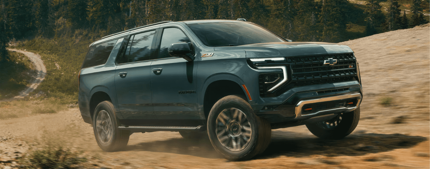 Green 2025 Chevy Suburban driving up a trail