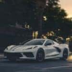 A white 2026 Chevy Corvette Stingray 3LT driving to a car dealership.