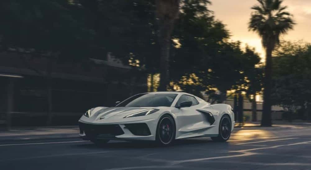 A white 2026 Chevy Corvette Stingray 3LT driving to a car dealership.