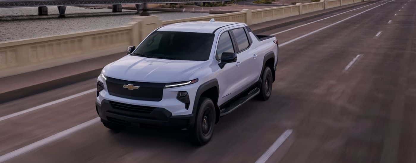 White 2025 Chevy Silverado EV WT driving over a bridge