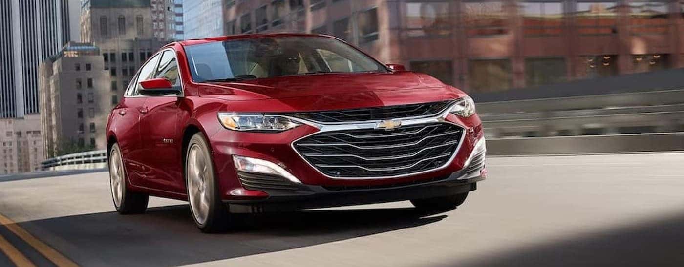 A red 2025 Chevy Malibu driving on a highway.