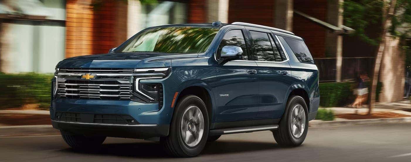 A blue 2026 Chevy Tahoe driving in a city.