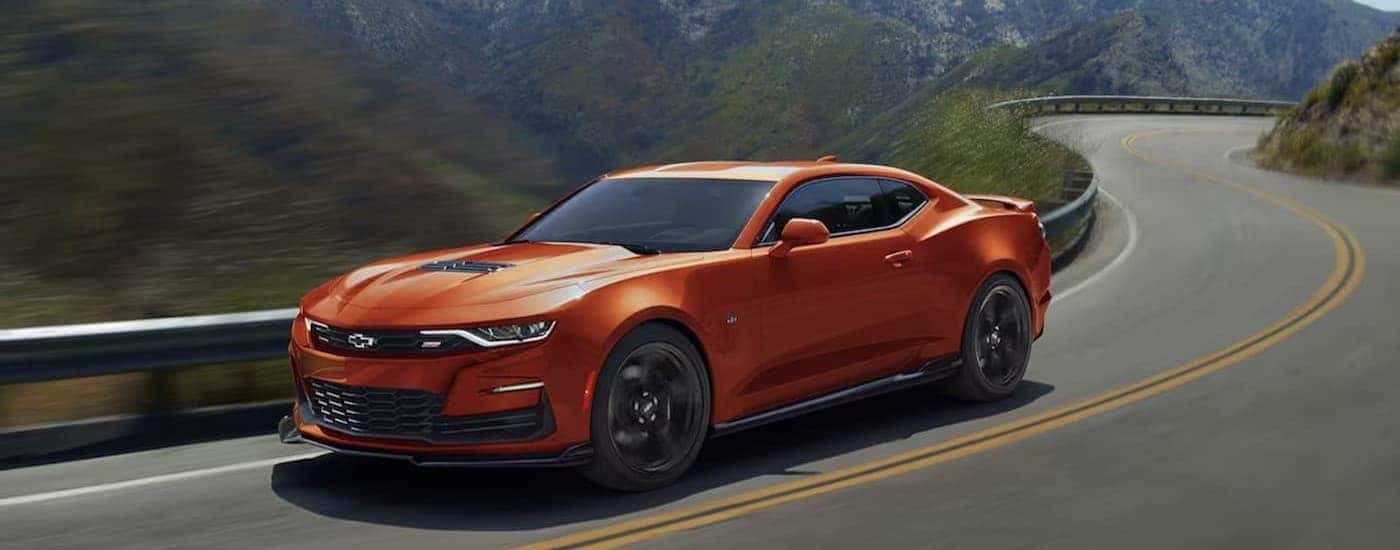 An orange 2024 Chevy Camaro driving on a highway.
