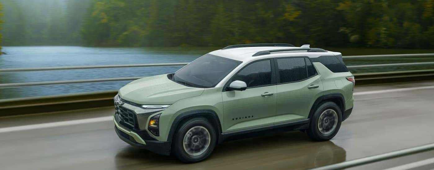A green 2026 Chevy Equinox ACTIV driving down a road