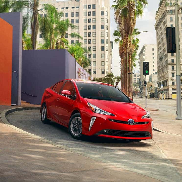Toyota Hybrid for Everyone at Penn Toyota | Red Toyota Prius Driving Driving Through City Streets