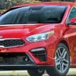 A red 2019 Kia Forte in front of a stone wall, from a Kia dealership near me