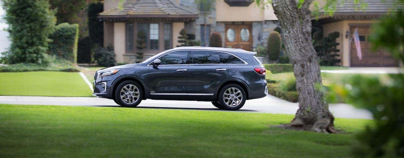 A gray 2019 Kia Sorento driving by an upscale home