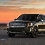 A green 2020 Kia Telluride, which can be ordered from a Kia dealership in NJ, is parked with a sunset behind it near Freehold, NJ.