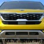 A yellow 2021 Kia Seltos, one of the upcoming Kia SUVs, is shown from the front in a field.